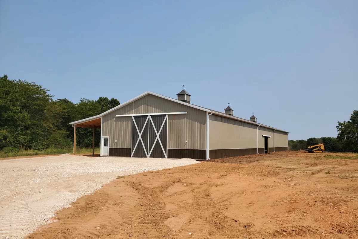 Tan post-frame shop with twin cupolas and crossbuck doors