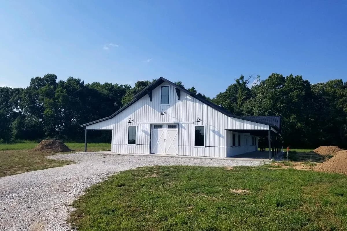 Farmhouse barndominium with barn doors and gooseneck lights